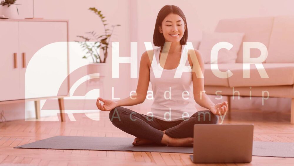 Keep Calm. Happy asian woman meditating with trainer online via laptop connection, copy space. Healthy lady sitting on the floor on yoga mat in lotus position, looking at computer and smiling